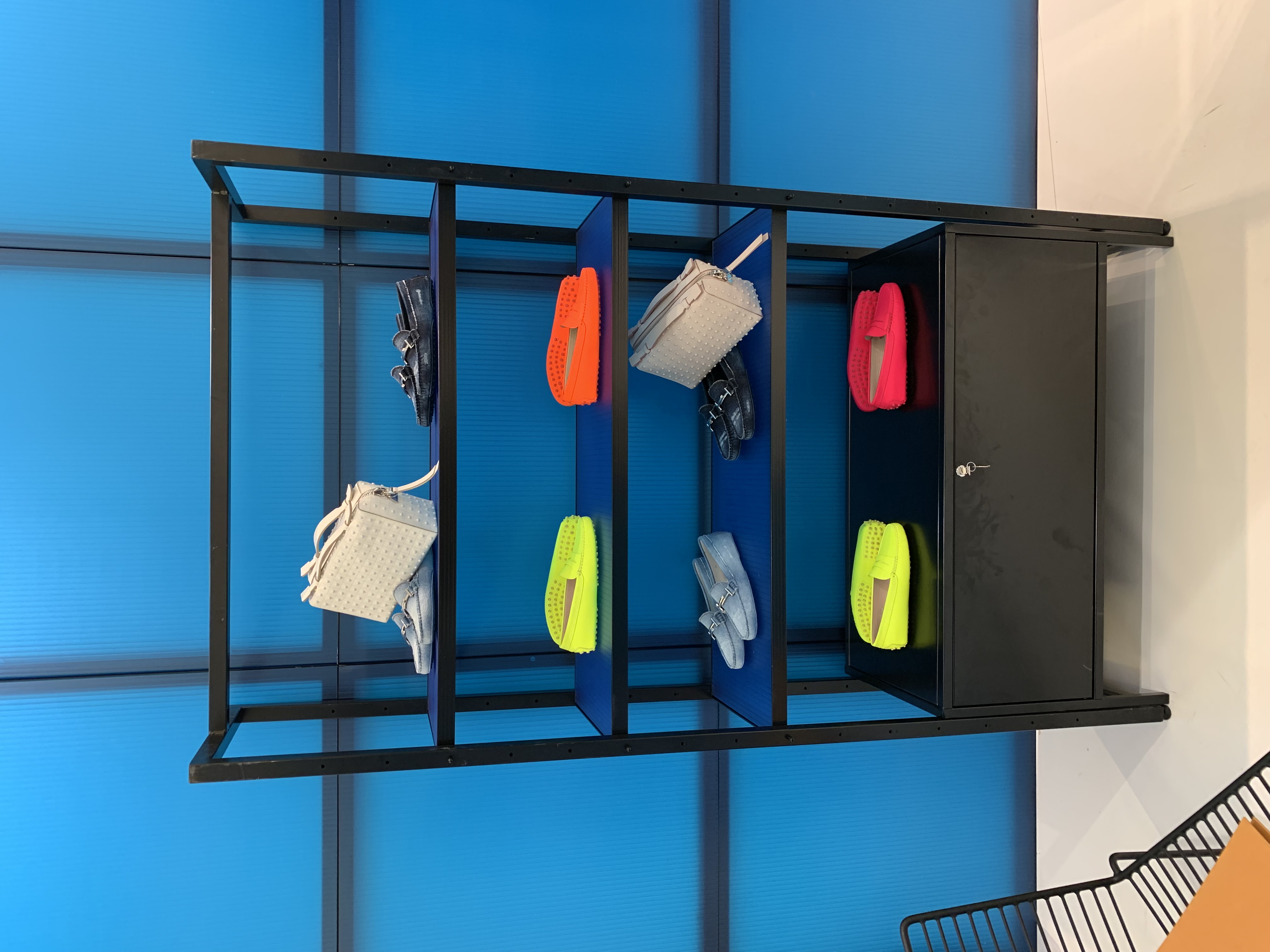 Étagères métal noir sacs colorés néon fond bleu